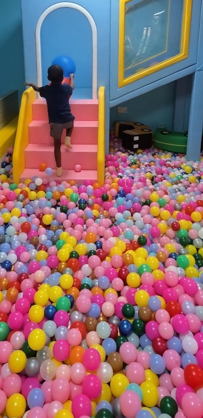 A child climbing the pink stairs beside Letzplay's giant ball pit, ready to jump back in.