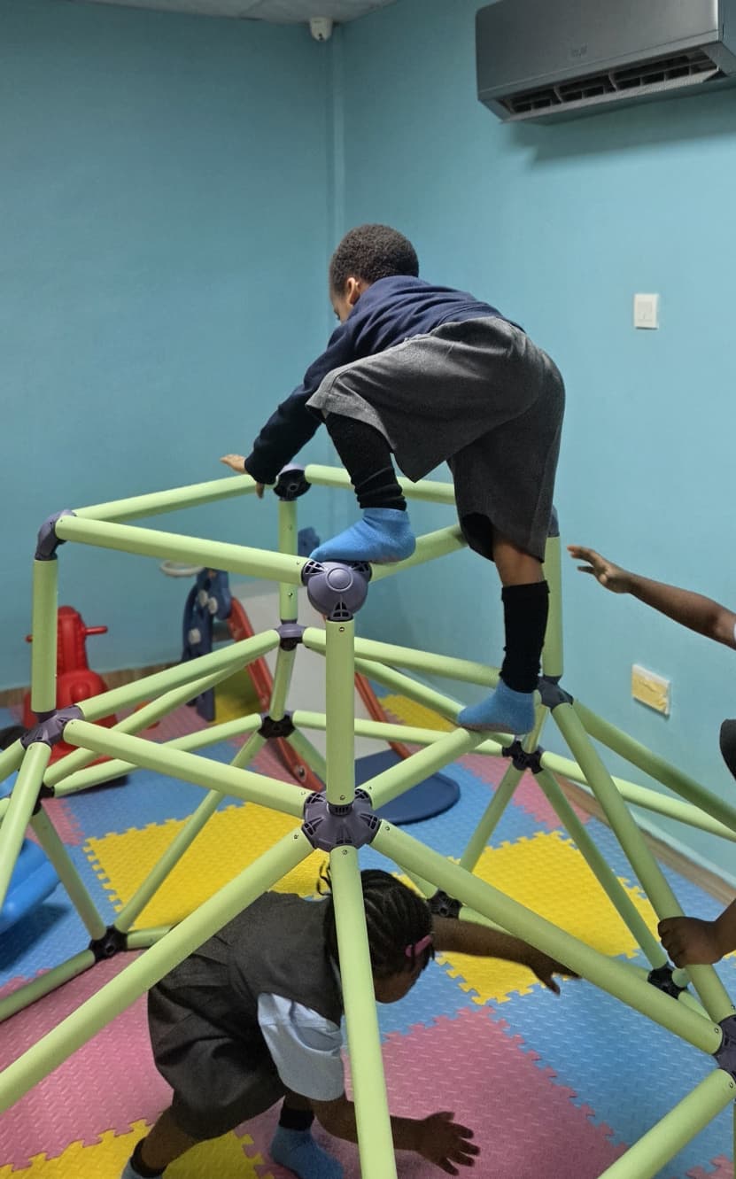 Kids climbing a dome climbing frame on the soft padded mats in Letzplay's toddler play room.
